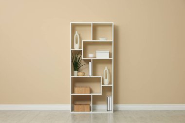 Shelving unit with decor near beige wall indoors