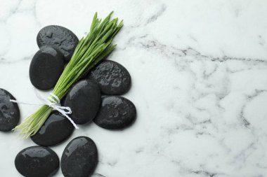 Spa stones and wheatgrass on white marble background, flat lay. Space for text