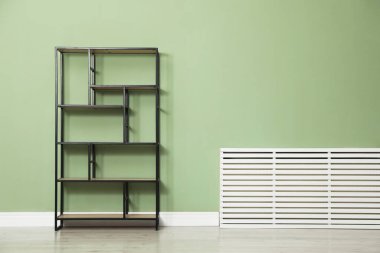 İçerideki zeytin duvarının yanındaki boş ahşap raf ünitesi.