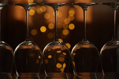 Bulanık ışıklara karşı cam ayna yüzeyinde birçok temiz bardak, yakın plan. Bokeh etkisi