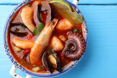 Lezzetli deniz ürünleri çorbası mavi ahşap masada, üst manzara.