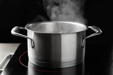 Kaynar su ve soba ile pişirme tenceresi siyah arka plan karşı, yakın çekim