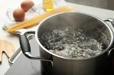 Tencereyi kaynar suyla pişirmek ve soba beyaz masada, yakın çekim.
