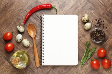 Boş yemek tarifi kitabı ve ahşap masa üzerindeki ürünler. Tasarım için model