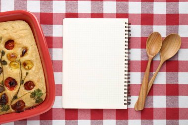 Boş tarif kitabı, turta ve kaşıklar kareli masa örtüsü, üst manzara. Tasarım için model