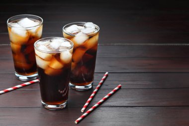 Kola bardakta buz ve tahta masada pipetle tazeleniyor. Metin için boşluk