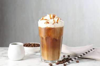 Krem şantili buzlu kahve, şurup ve beyaz mermer masada fasulye.