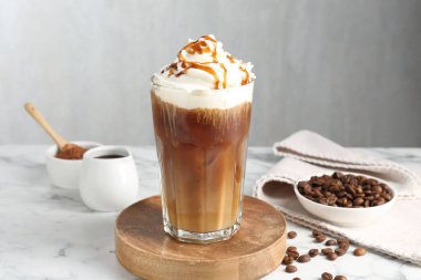 Krem şantili buzlu kahve, şurup ve beyaz mermer masada fasulye.