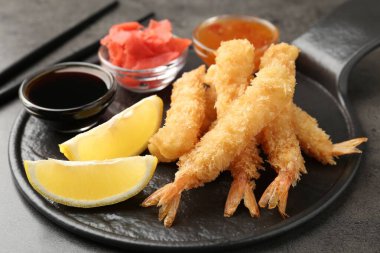 Lezzetli tempura karidesleri, limon, zencefil ve soslar gri desenli masada, yakın plan.