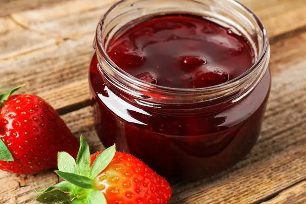 Lezzetli çilek sosu ve ahşap masada taze böğürtlen, yakın plan.