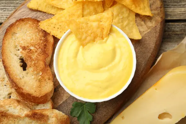 Lezzetli peynir sosu kasede, nacho cipsi ve ekmek kırıntıları ahşap masada, düz yatıyordu.