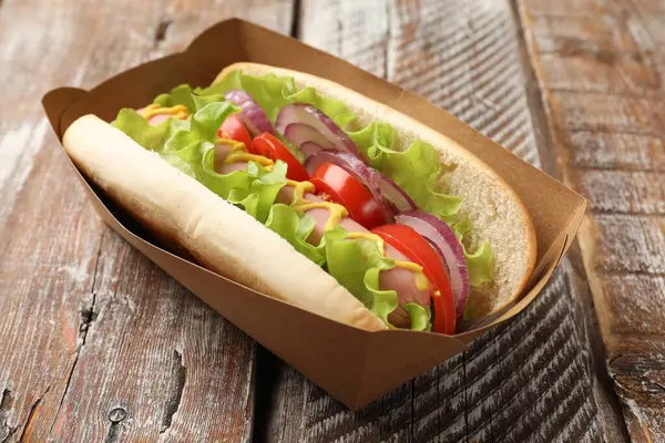 Lezzetli sosisli, domates, soğan, marul ve hardal, ahşap masa, yakın plan.