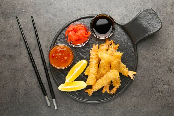 Lezzetli tempura karidesleri limon, zencefil ve sosla servis edilir gri desenli masa, düz uzanma