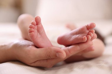 Anne, küçük bebeği evde, yatağında, yakın plan.