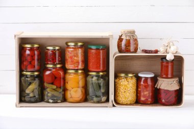 Beyaz masa üzerinde farklı turşu ürünleri ve malzemelerle dolu bir sürü kavanoz.