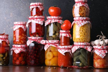 Pek çok kavanoz farklı turşu ürünleri ve malzemeler ahşap masada.