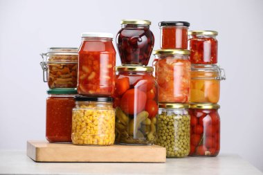 Açık gri masada farklı turşu ürünleri olan bir sürü kavanoz.