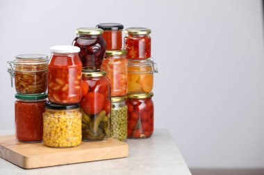 Açık gri masa üzerinde farklı turşu ürünleri olan birçok kavanoz, metin için boşluk