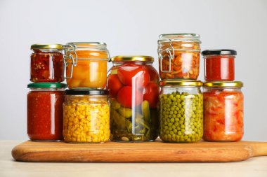 Açık gri arka planda farklı turşulu pek çok kavanoz var.