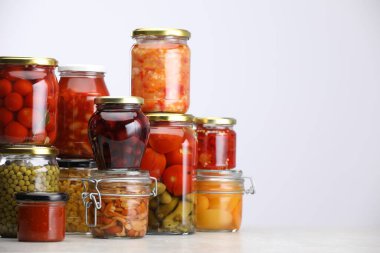 Açık gri masa üzerinde farklı turşu ürünleri olan birçok kavanoz, metin için boşluk