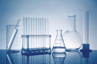 Ayna yüzeyinde ışık arkaplanına karşı sıvı bulunan laboratuvar camları
