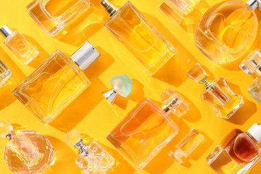 Sarı arka planda çeşitli parfüm şişeleri, düz yatıyordu.