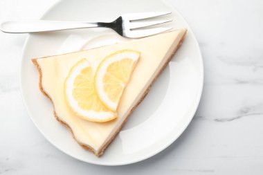 Beyaz mermer masada servis edilen lezzetli limonlu cheesecake.