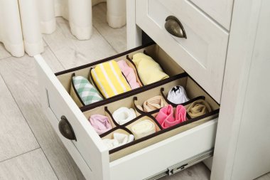 Organizers with folded clothes in drawer indoors, closeup