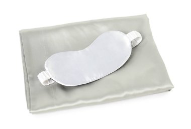 Beyaz arka planda ipek çarşaflar ve uyku maskesi.