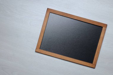 Hafif ahşap zemin üzerinde boş küçük karatahta, üst görünüm