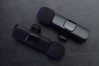 Lavalier mikrofonları siyah masada, düz yerde.