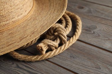 Ahşap arka planda pamuk ip ve hasır şapka, yakın plan.