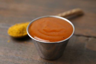 Metal tabakta köri sosu ve ahşap masada toz, yakın plan.