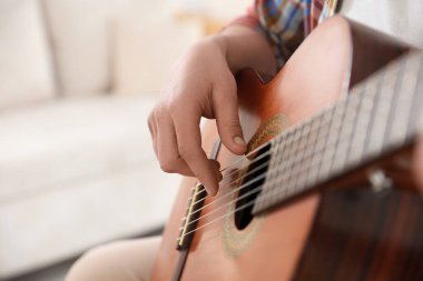Evde gitar çalan adam, eline odaklan. Metin için boşluk
