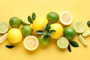 Sarı zemin üzerinde taze limon ve limon, düz uzanmış.