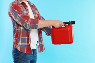 Açık mavi arka planda plastik kutu tutan adam, yakın plan.