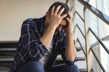 Binanın merdivenlerinde oturan bunalımlı adam.