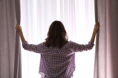 Evde perdeleri açan kadın, arka manzara