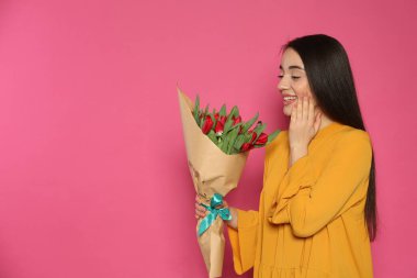 Kırmızı lale çiçekli mutlu kadın pembe arka planda, mesaj için yer var. 8 Mart kutlamaları