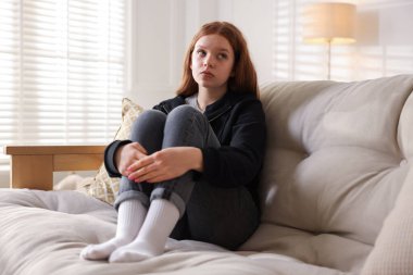 Evdeki kanepede oturan üzgün genç kız.