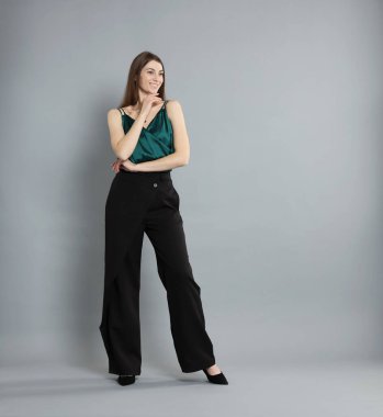 Gri arka planda şık giyinmiş güzel bir kadın.