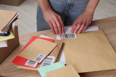 Barkodları postanedeki zarflara koyan kadın, yakın plan.