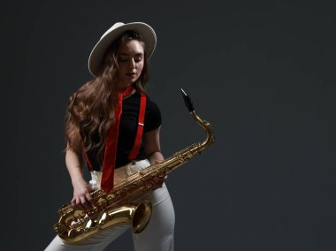 Gri arka planda saksafonu olan profesyonel bir müzisyen. Metin için boşluk