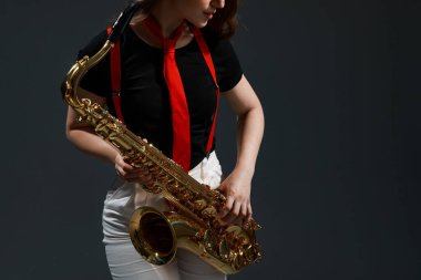 Gri arka planda saksafonu olan profesyonel bir müzisyen, yakın plan. Metin için boşluk