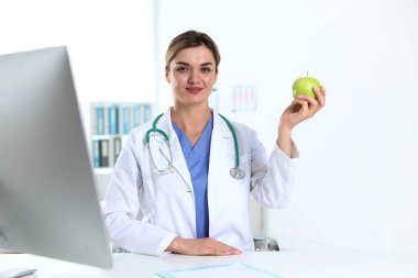 Klinikteki masada yeşil elmalı ve steteskoplu beslenme uzmanı.