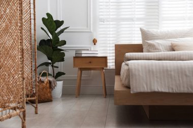 Rahat yatak, komodin ve bitki şık bir odada. İç tasarım