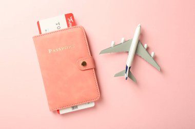 Pasaport ve uçak modeli pembe arka planda, düz yatıyordu.