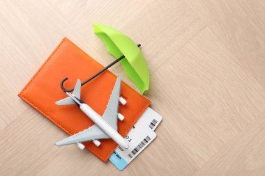 Seyahat sigortası. Uçak modeli, pasaport, küçük şemsiye ve tahta masa üzerindeki biletler. Metin için boşluk