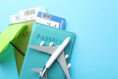 Seyahat sigortası. Uçak modeli, pasaportlar, küçük şemsiyeler ve açık mavi arka planda biletler. Metin için boşluk