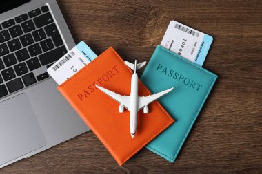 Pasaportlar, uçuş biletleri, uçak modeli ve dizüstü bilgisayar ahşap masada, düz konum